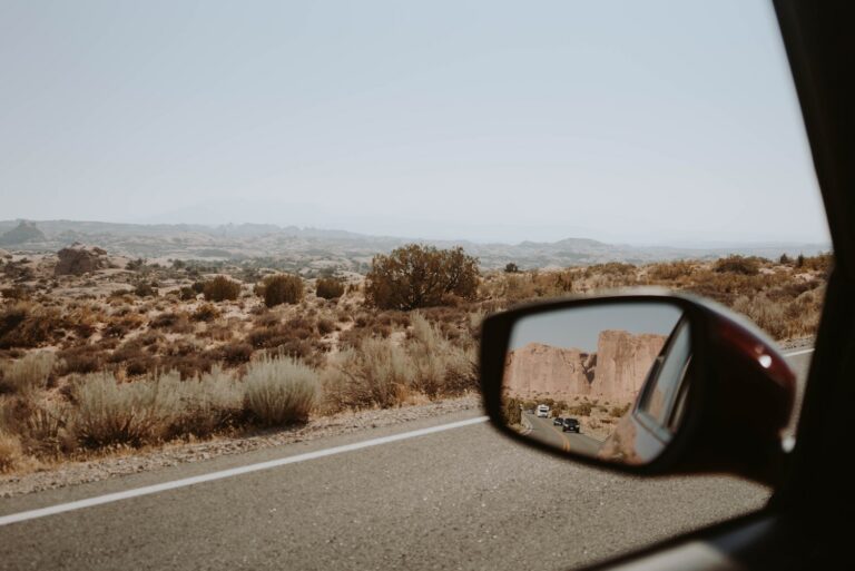 A picture of the road behind taken through side mirror of a car
