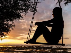 Female sitting on a swing, watching the sunset