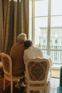 Elderly couple sitting in chairs and looking out the window.