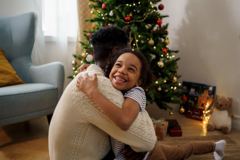 Girl hugging father on Christmas in front of Christmas tree