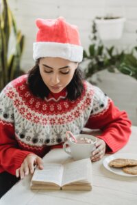 Girl reading a book with hot chocolate at Christmas
